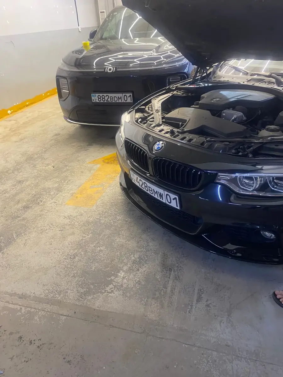 Чёрный BMW M с открытым капотом в цеху